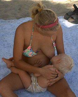 breastfeeding mom on beach with 1-year old